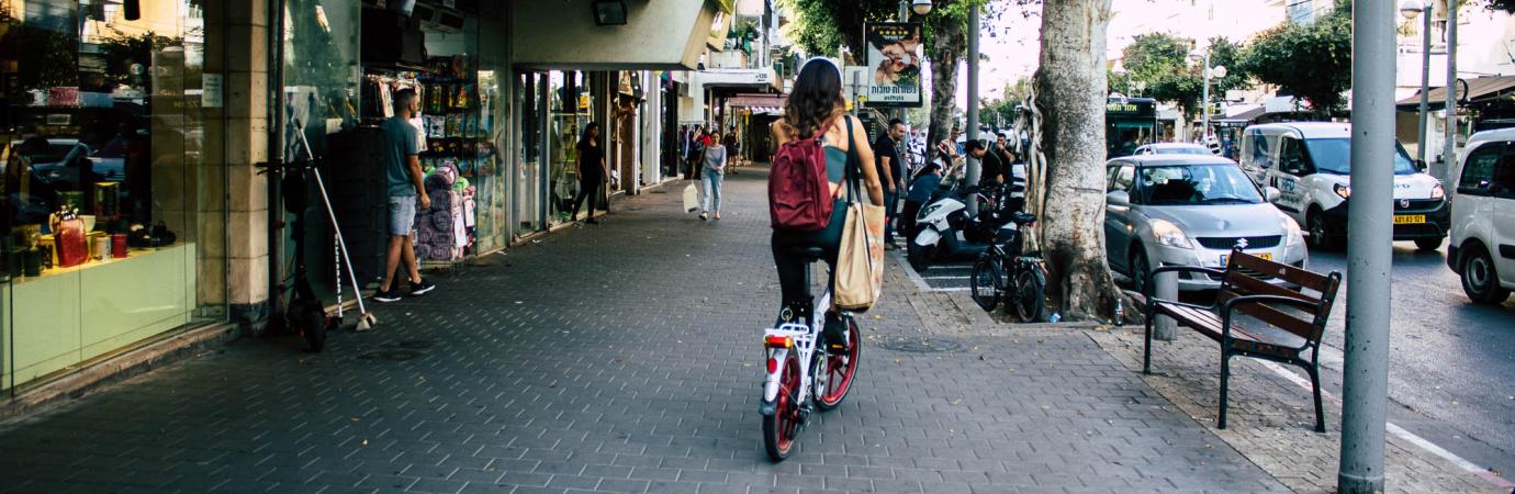 A woman commutes by bicycle through the streets of Tel Aviv, Israel. Editorial credit: Jose HERNANDEZ Camera 51 / Shutterstock.com.