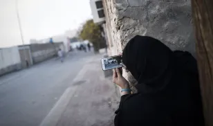 A Bahraini woman uses a mobile phone to take photos during clashes with riot police in Sitra, south of the capital Manama, January 2016. Photo credit by Mohammed al-Shaikh/AFP/Getty Images