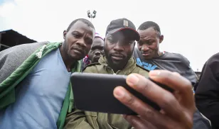 Kenyans watch the announcement of the presidential results on the phone at the Gikomba market in Nairobi.