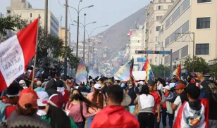Protesters in Lima draped with Peruvian flags and waving Wiphalas.