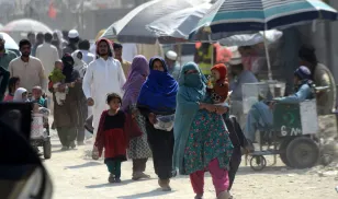 Afghan families wait for completion of the immigration process at the Torkham border before crossing back into their country. 