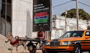A man rides a cart past a poster advocating for an end to female genital mutilation (FGM), in Banjul, Gambia