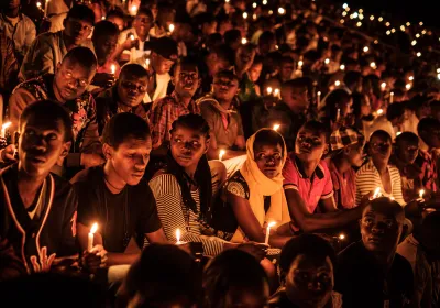People hold candles as they attend a night vigil and prayer at the Amahoro Stadium as part of the 25th Commemoration of the 1994 Genocide.  Kigali, Rwanda. 7 April 2019. Editorial credit: Editorial Credit: YASUYOSHI CHIBA/AFP via Getty Images