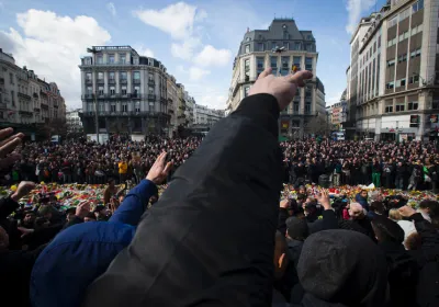 Masked and hooded men gesture outside the stock exchange in Brussels on March 27, 2016 as tensions mounted after the square was invaded by some 200 far-right football hooligans, during a tribute to the victims of the Brussels terror attacks. 