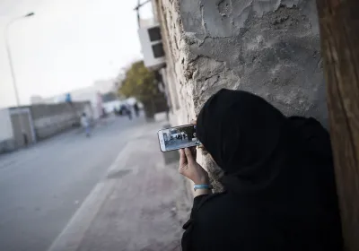 A Bahraini woman uses a mobile phone to take photos during clashes with riot police in Sitra, south of the capital Manama, January 2016. Photo credit by Mohammed al-Shaikh/AFP/Getty Images