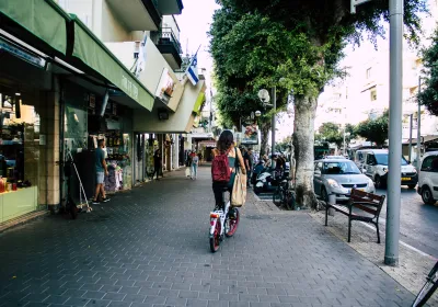 A woman commutes by bicycle through the streets of Tel Aviv, Israel. Editorial credit: Jose HERNANDEZ Camera 51 / Shutterstock.com.