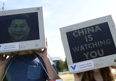 demonstrators hold desktop monitors with protest images