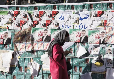 Iranian Woman views phone next to campaign photos