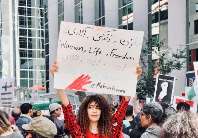 Woman Holding protest sign reading "women, life, freedom"