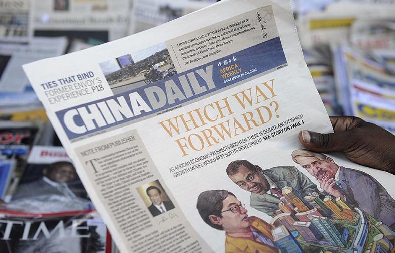 A newspaper consumer reads a copy of the Africa edition of Beijing’s state-run China Daily newspaper in front of a newsstand in Nairobi, Kenya. Photo Credit: TONY KARUMBA/AFP/Getty Images.